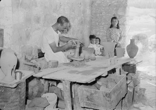 A Palestinian potter at his wheel in Nazareth in July 1940, photographed at the table with a partly formed vessel in his hands