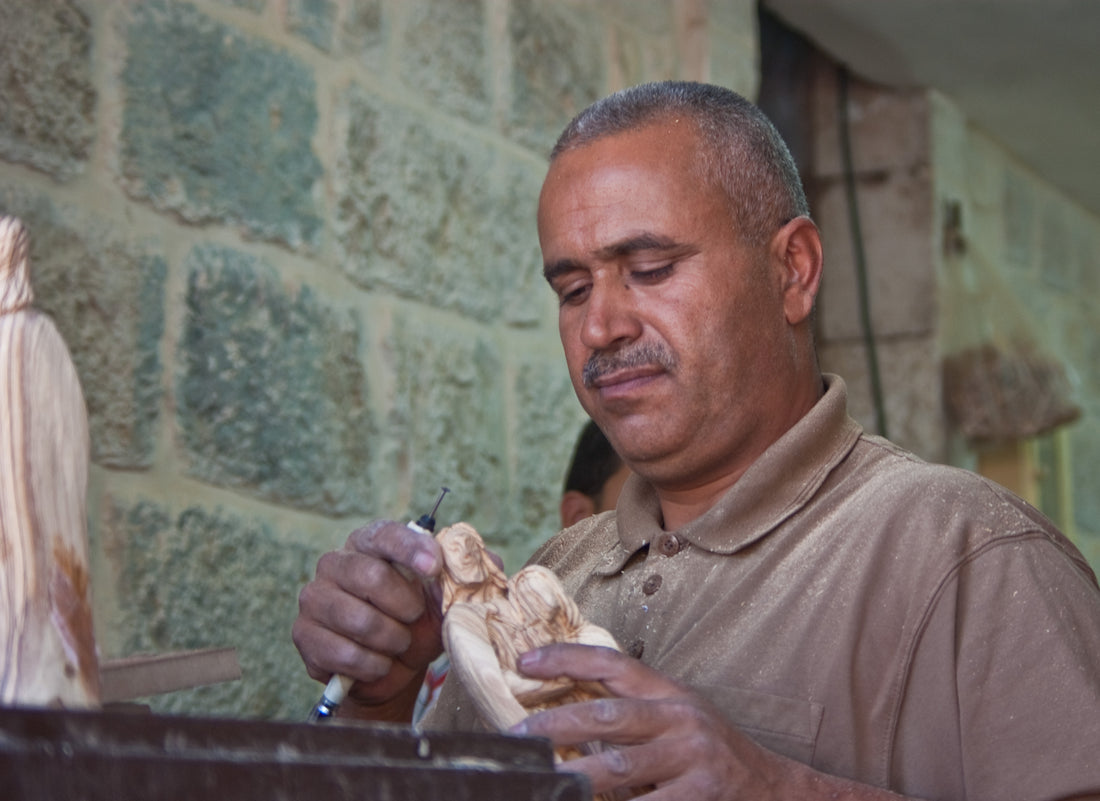 A Palestinian craftsman carving a figure from olive wood at his bench in a Bethlehem workshop