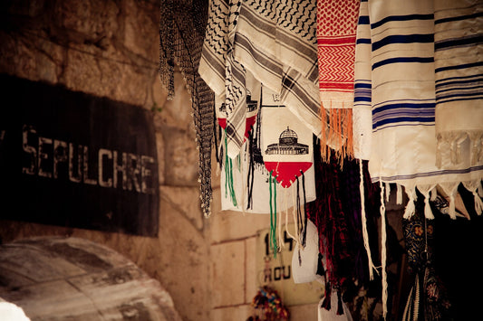 Keffiyehs in black and white and red and white hanging for sale in a market stall in Jerusalem's Old City