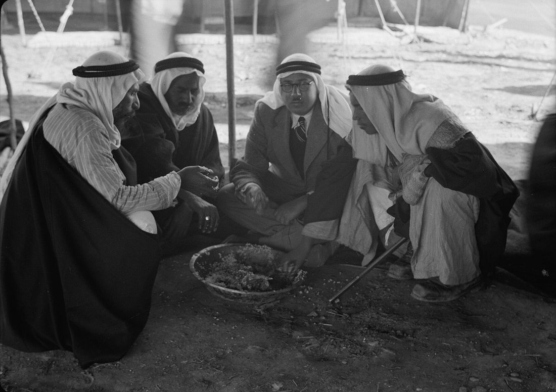 Four Palestinian men wearing white keffiyehs bound with black agal cords, seated at a tribal gathering near Beersheba in 1940
