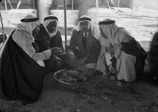 Four Palestinian men wearing white keffiyehs bound with black agal cords, seated at a tribal gathering near Beersheba in 1940