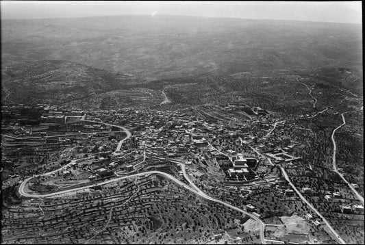 A mid-20th-century aerial photograph of Bethlehem and its surrounding hillsides, terraced fields and olive groves spreading across the slopes below the town