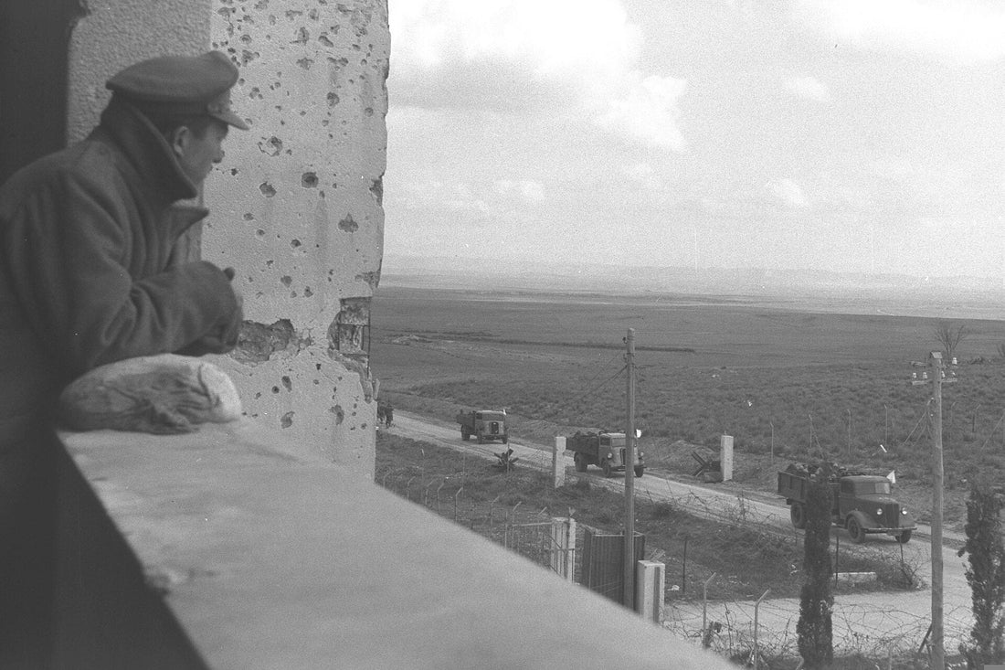 An Israeli officer looks out from a bullet-scarred building over the road near Al-Faluja, Palestine, during the evacuation of the Faluja Pocket, 1949
