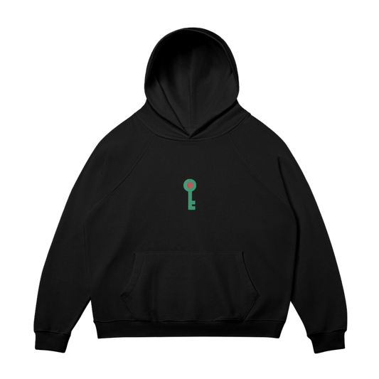 Front view of the Key of Return Hoodie in black, featuring a green key emblem symbolizing Palestinian heritage. Set against a transparent background.