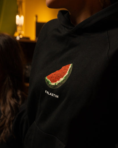 Black hoodie with Palestinian watermelon design and 'FALASTIN' text on a dark background