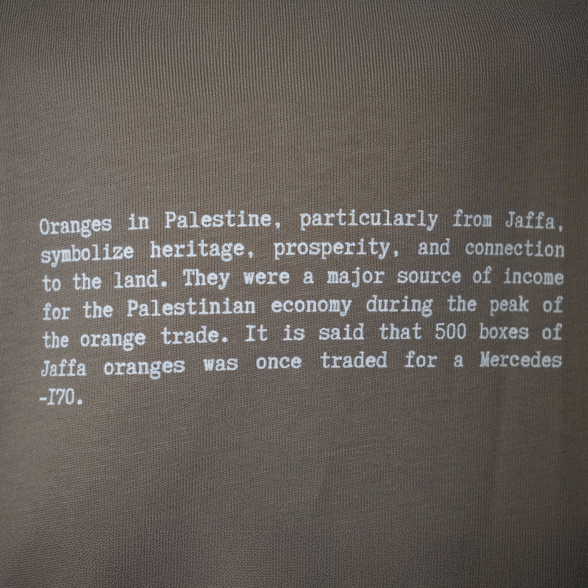 A close-up image of the front text on the Heritage Olive Tree T-Shirt in Coffee from FALASTIN, highlighting the message about the Palestinian olive tree as a symbol of resilience, peace, and rootedness, deeply connected to the land and identity.