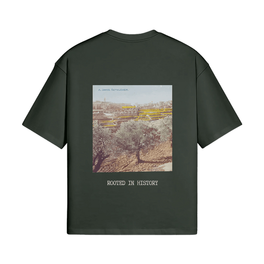 A mockup image of the Heritage Olive Tree T-Shirt in forest from FALASTIN, showcasing the back design featuring a vibrant illustration of a Palestinian olive tree and the words ‘Rooted in History.’ The design is displayed on a transparent background, emphasizing the deep forest green color of the t-shirt and its connection to Palestinian heritage.