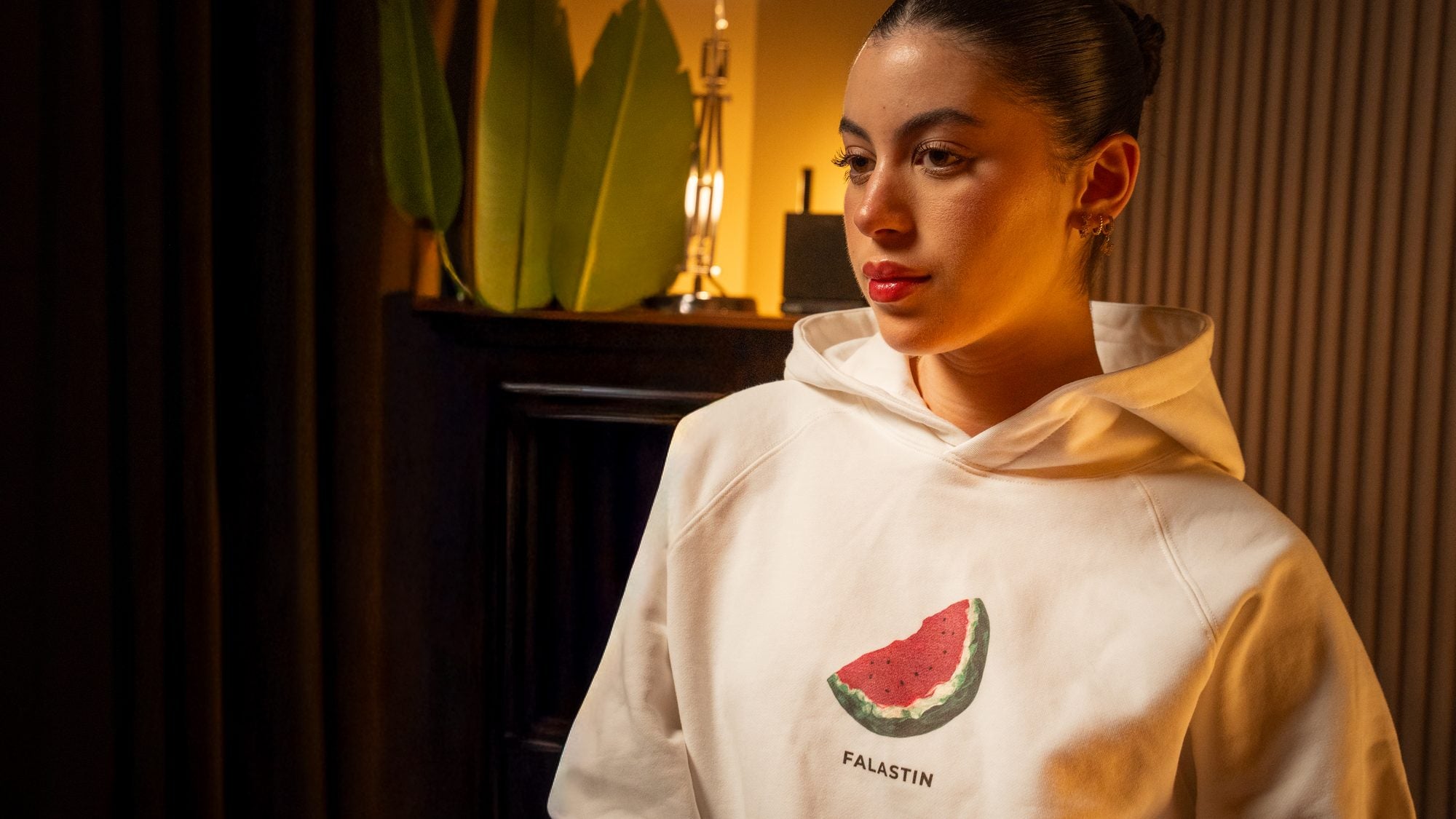 Woman wearing the FALASTIN watermelon embroidered hoodie in cream, Palestinian heritage streetwear